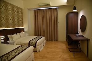Une chambre d’hôtel avec deux lits, un bureau, un miroir et un appareil de climatisation.