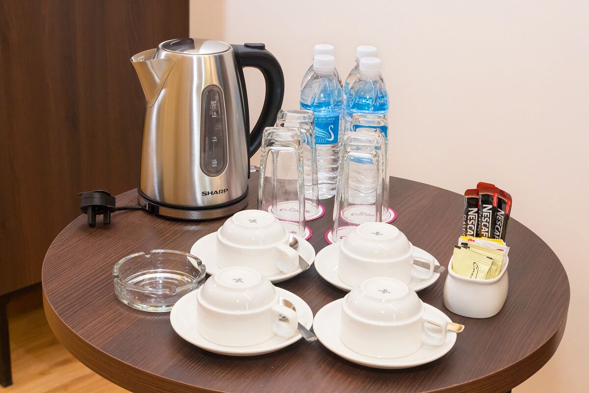 A table with a coffee maker, water bottles, and tea sets.