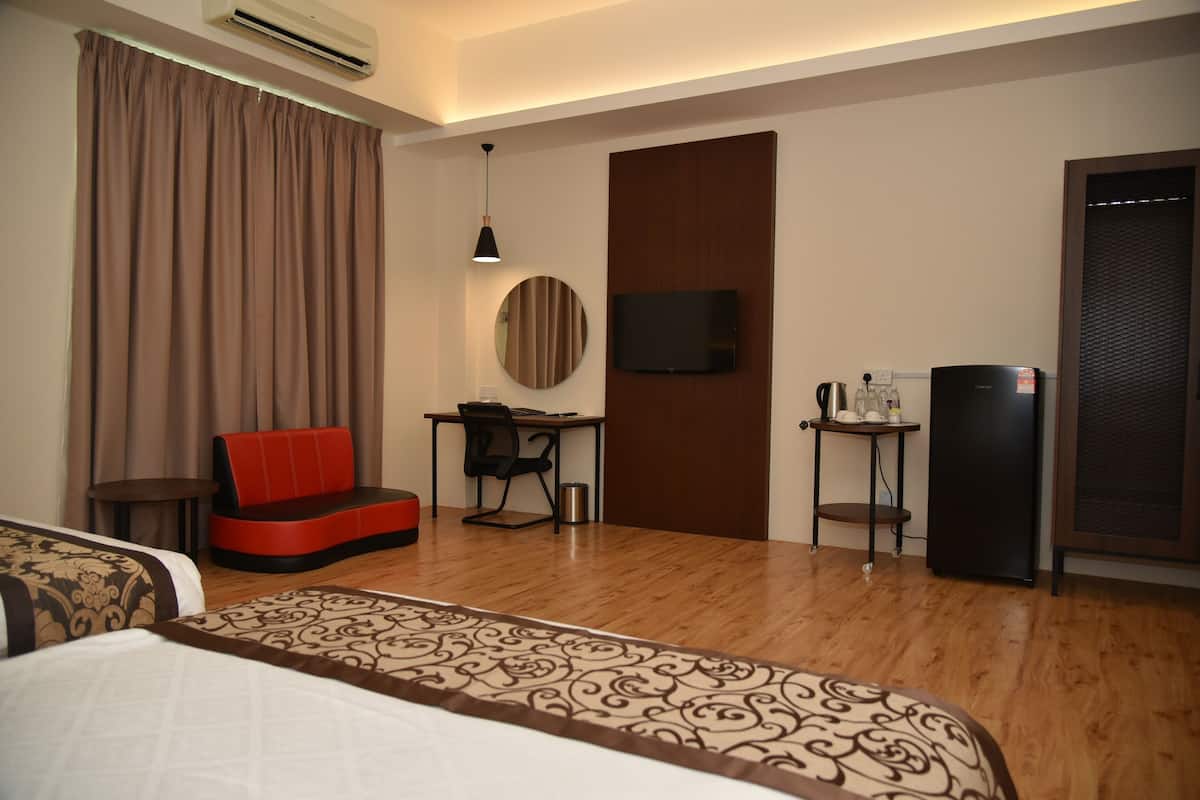 A hotel room with a bed, a desk with a chair, a television, and a refrigerator.