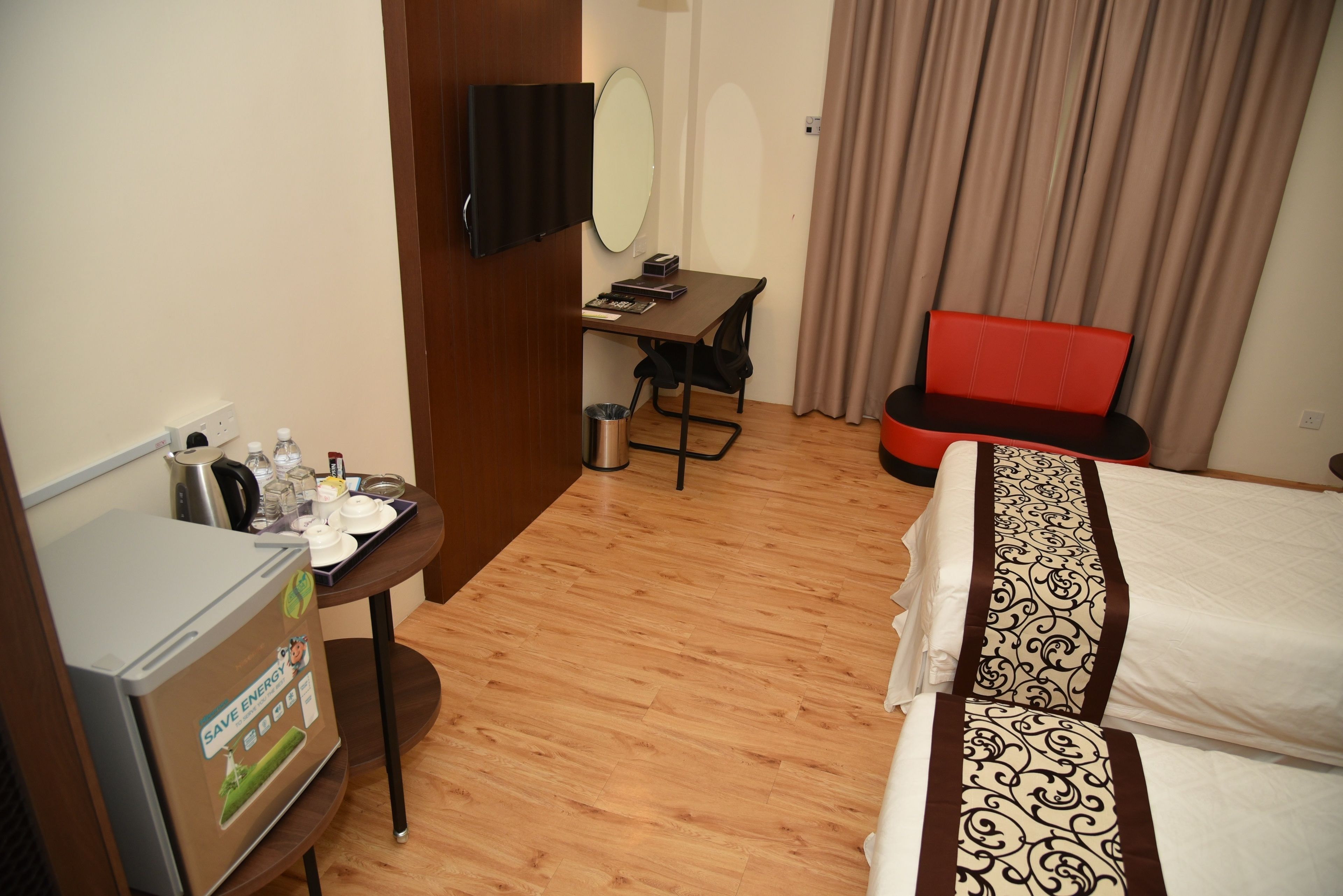 Habitación de hotel con cama, escritorio, silla, televisión y minibar.