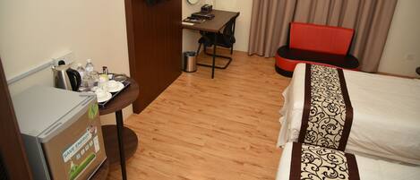 Habitación de hotel con cama, escritorio, silla, televisión y minibar.