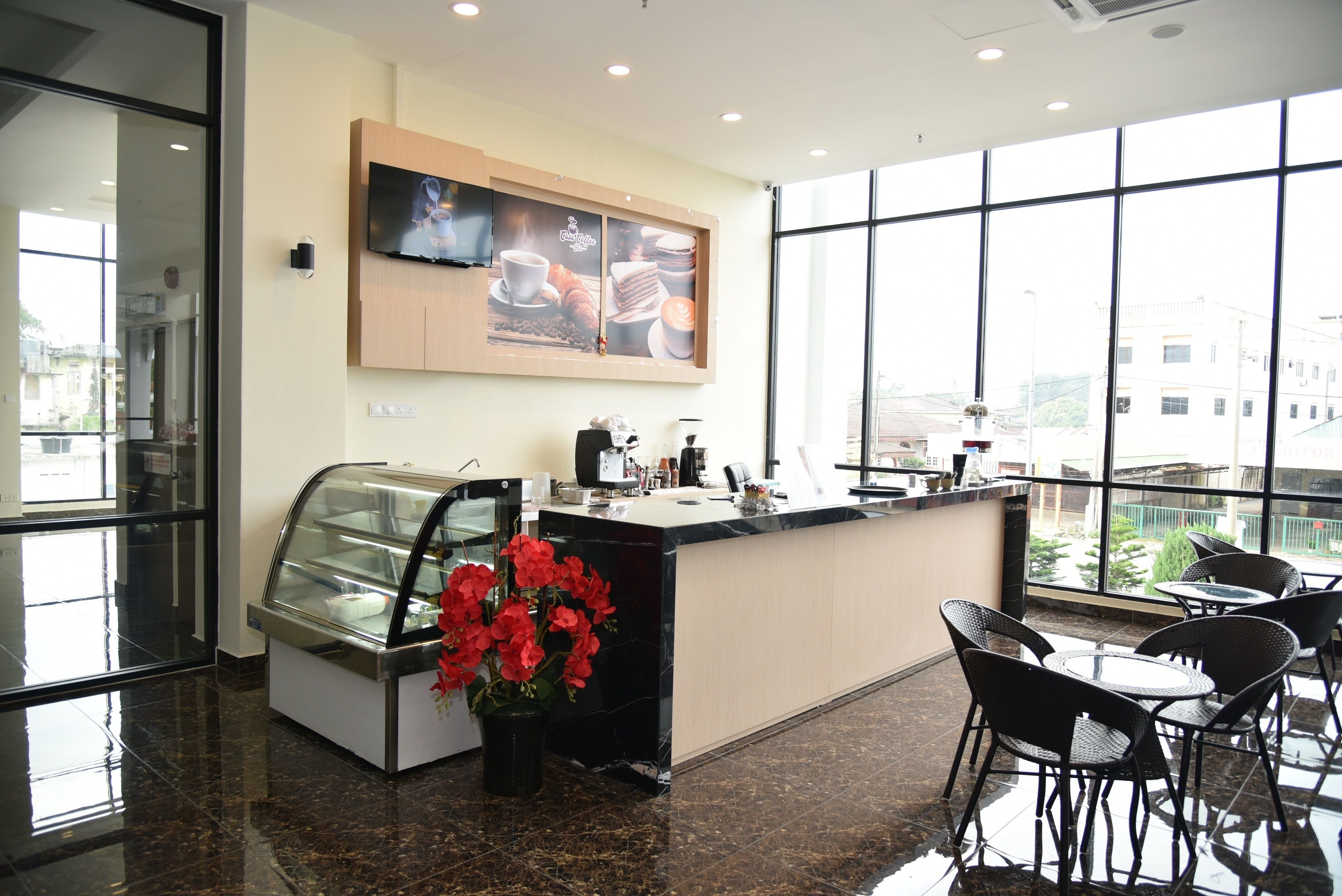 Una cafeteria moderna amb una vitrina, una màquina de cafè i un gran finestral que ofereix vistes a la ciutat.