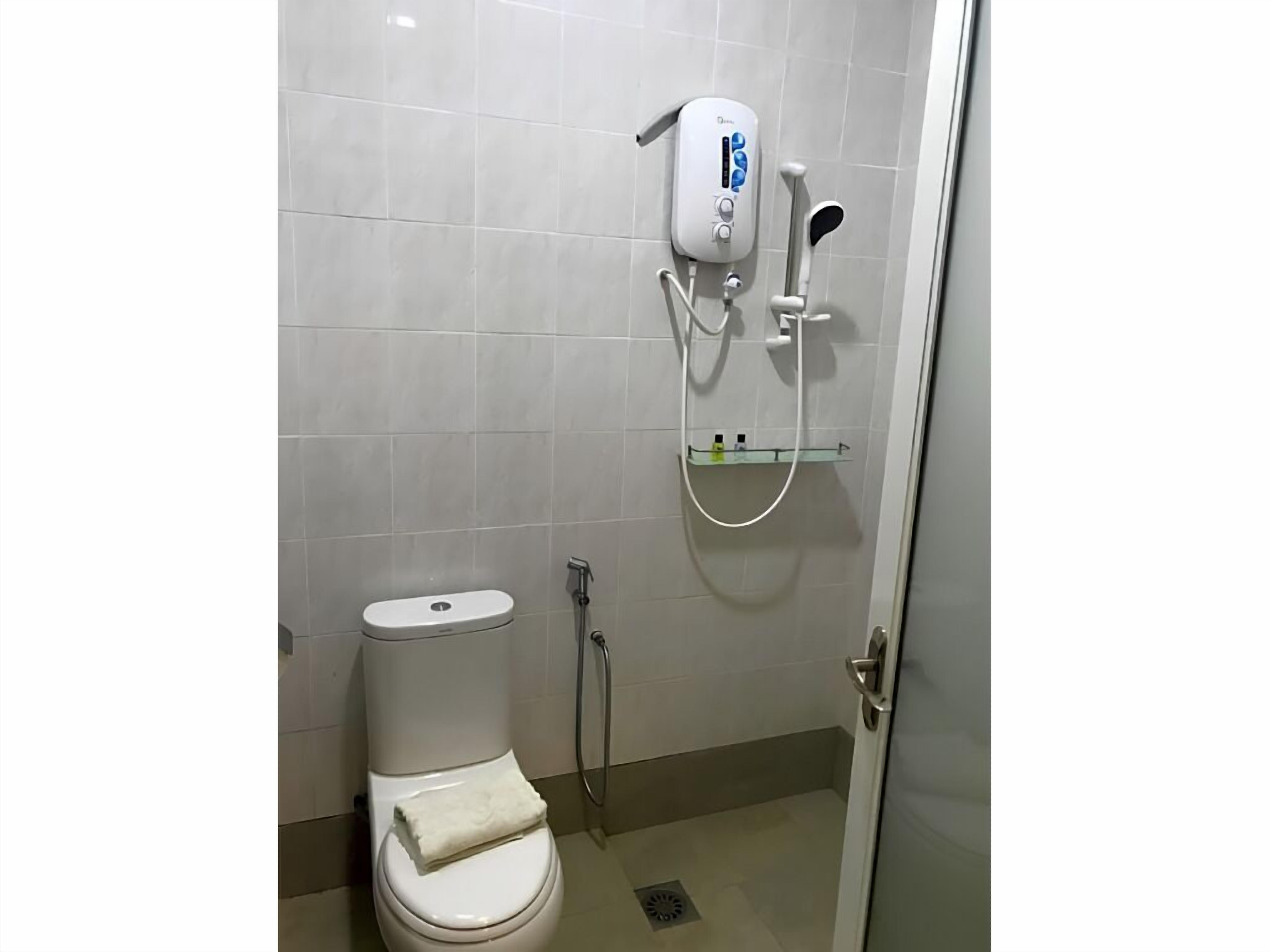 Een badkamer met een toilet, een handdouche en een muurkraan.