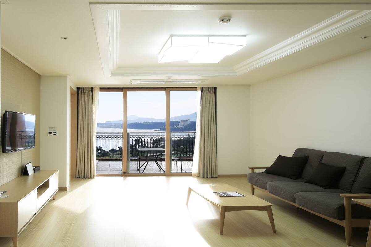 Une chambre d’hôtel moderne dotée d’un balcon, d’un canapé, d’une télévision et d’une table basse en bois.