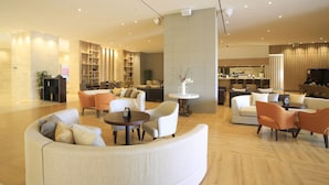 A spacious lobby with multiple seating areas, a reception desk, and a bar area. - Jeju Booyoung Resort (Seogwipo)