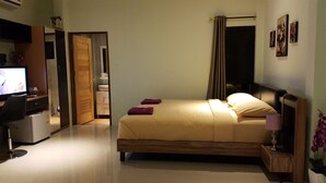 Une chambre d’hôtel avec un lit, un bureau équipé d’un ordinateur, une télévision et une salle de bain visible à travers une porte ouverte.