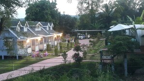 Une rangée de bâtiments de style traditionnel, avec un trottoir pavé et des espaces verts aménagés en jardin.