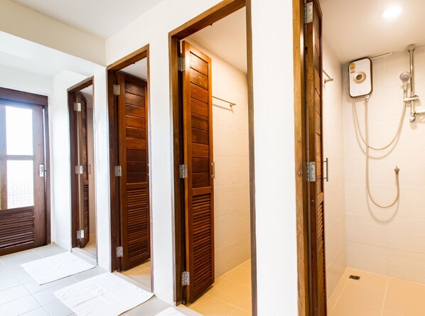 Habitación de hotel con puertas de madera, ducha y suelo de baldosas.
