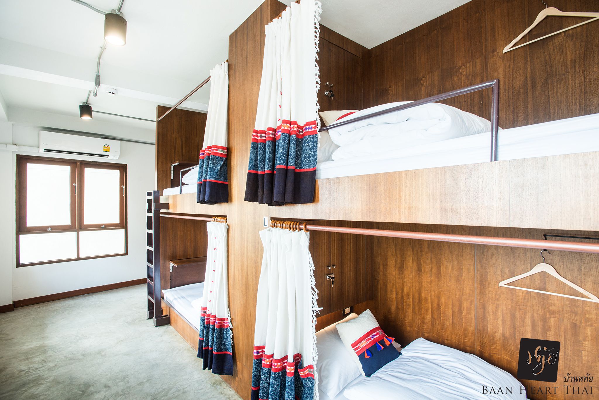 A room with bunk beds, wooden walls, a window, and an air conditioning unit.