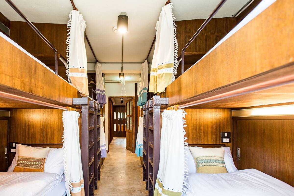 Een treinwagon met houten wanden, twee bedden met witte lakens en muggennetten.