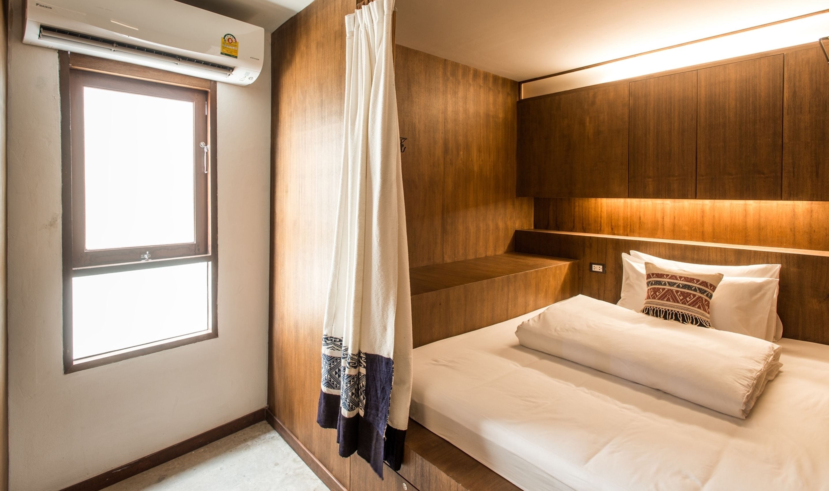 A hotel room with a bed, a window, and a wooden wall.