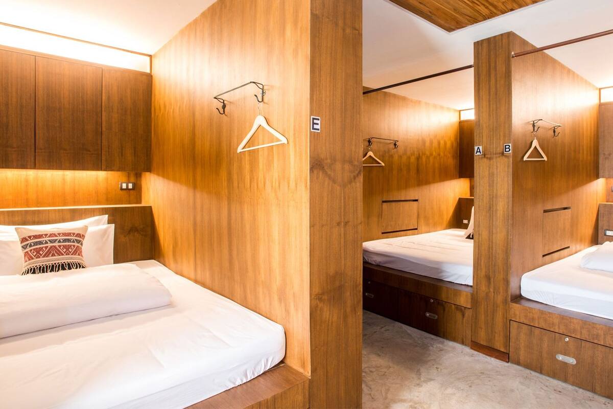 Een hotelkamer met houten lambrisering, twee bedden, een garderobe en een spiegel.