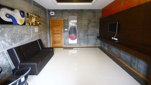 Um lobby moderno com um sofá de couro preto, uma porta de madeira e arte abstrata nas paredes.