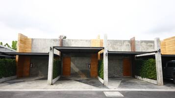 Un edificio moderno con un'area di parcheggio coperta, pareti in cemento e porte in legno.