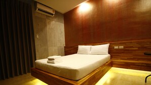 Quarto moderno com cabeceira de madeira, cama bem arrumada com roupa de cama branca e piso de madeira.