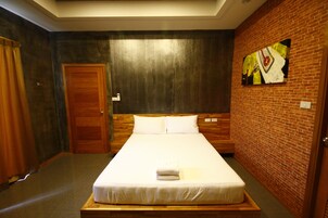 Habitación de hotel con una cama grande, cabecero de madera, pared de ladrillo y un cuadro.