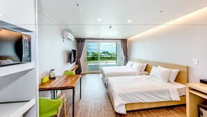 Een moderne hotelkamer met twee bedden, een bureau, een stoel, een televisie en uitzicht op het omliggende landschap.