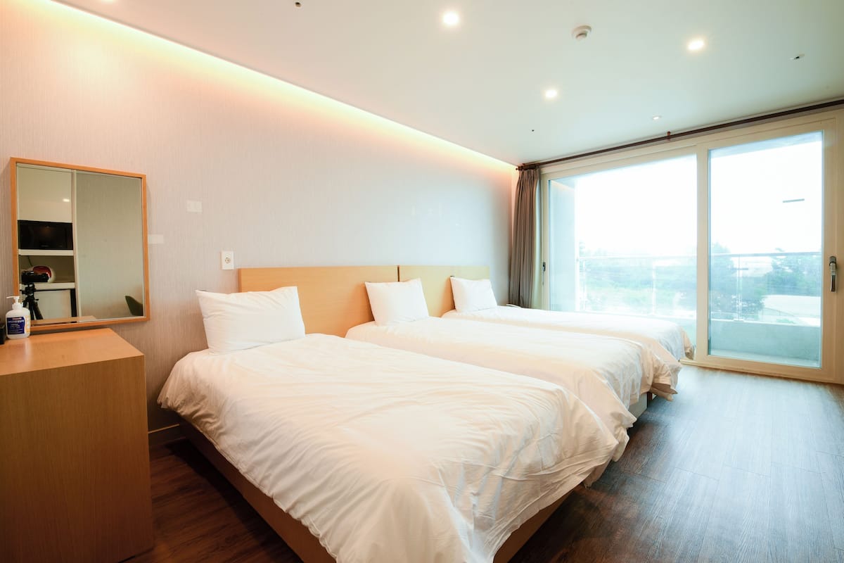 Ein Hotelzimmer mit zwei Betten, einem Holzschrank, einem großen Spiegel und einer Glastür zum Balkon.