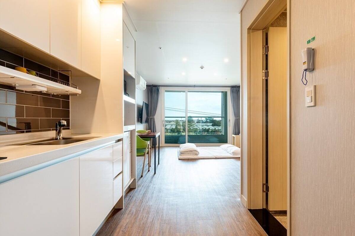 Ein modernes Hotelzimmer mit Küchenzeile, einem großen Fenster und Stadtblick sowie einem Bett mit Blick.