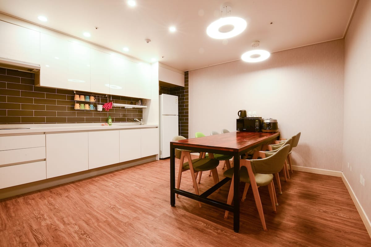 Eine moderne Küche mit weißen Schränken, einem Holztisch und grünen Stühlen.