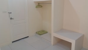 A small, clean room with a white door, a green towel on a rack, and a white bench. - The Homestead Resort Pakchong (Pak Chong)