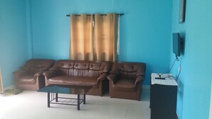 A living room with a brown leather sofa, a glass coffee table, and a TV on a stand. - The Homestead Resort Pakchong (Pak Chong)