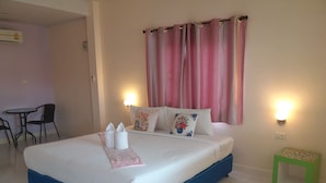 A neatly made bed with pillows and a pink towel, a small green side table, and a chair in a room with a tiled floor. - The Homestead Resort Pakchong (Pak Chong)