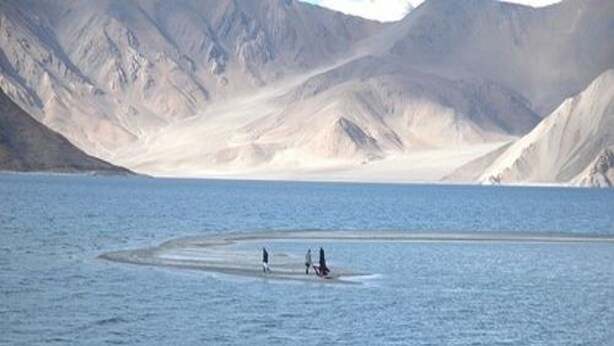 A large body of water with a small island and mountains in the background. - The Buddha Camp (Leh)