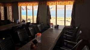 A dining area with a long table, chairs, and a view of the beach. - The Buddha Camp (Leh)
