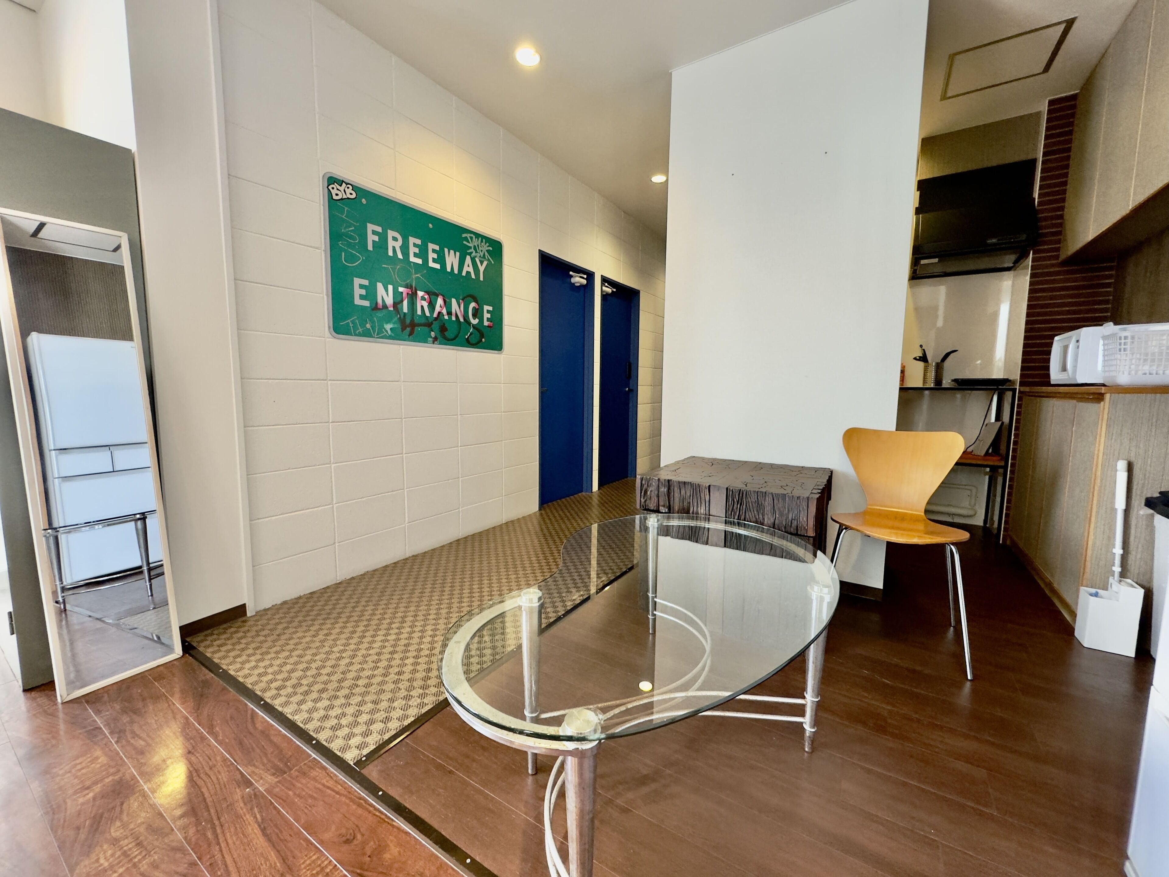 A modern interior with a glass table, a blue door, and a sign indicating a freeway entrance.