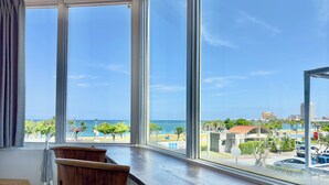 A room with large windows overlooking a beach and cityscape. - Araha Resort ARAPANA (Chatan)