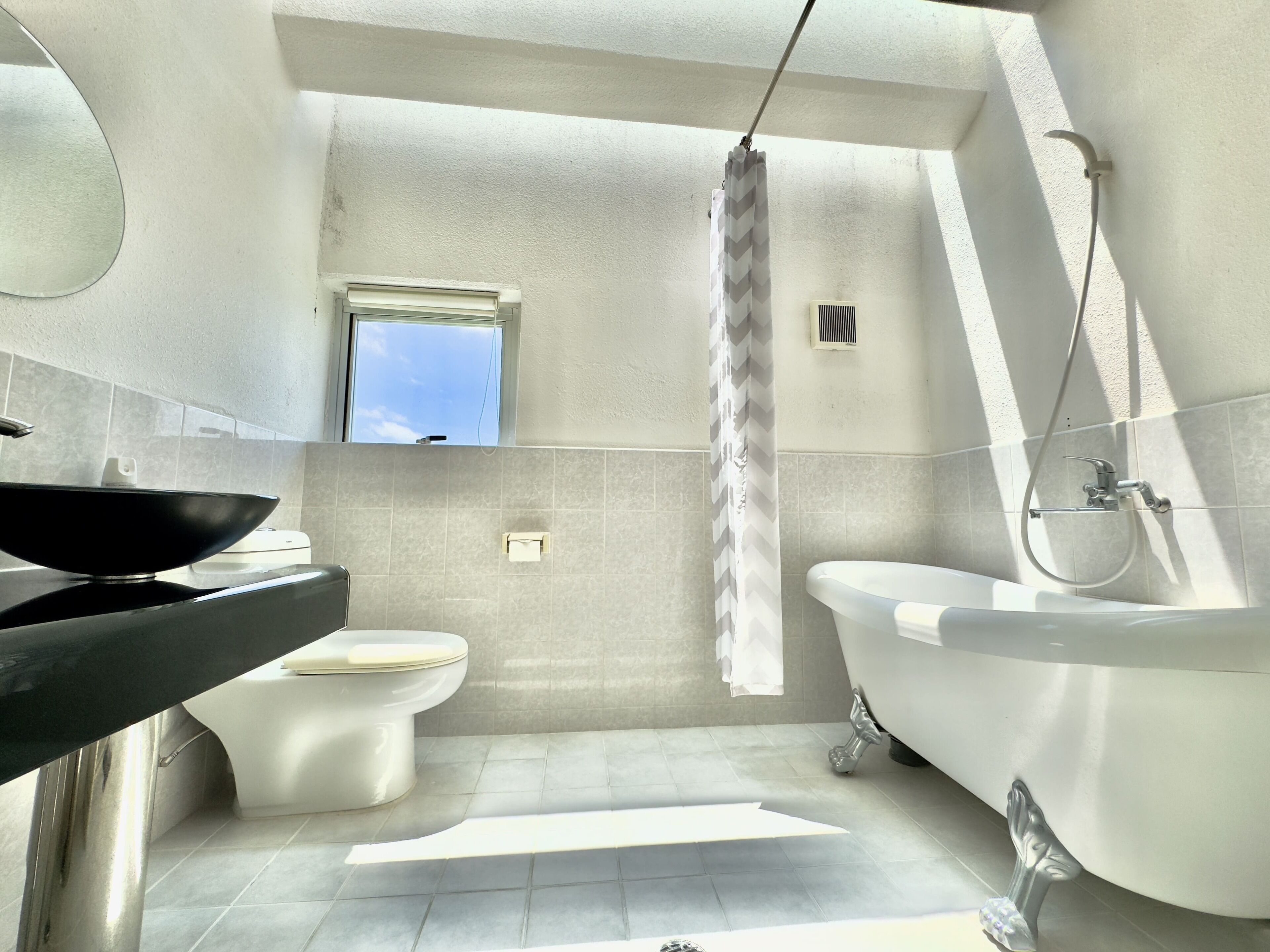 Un baño moderno con una bañera independiente, un inodoro y un espejo grande.