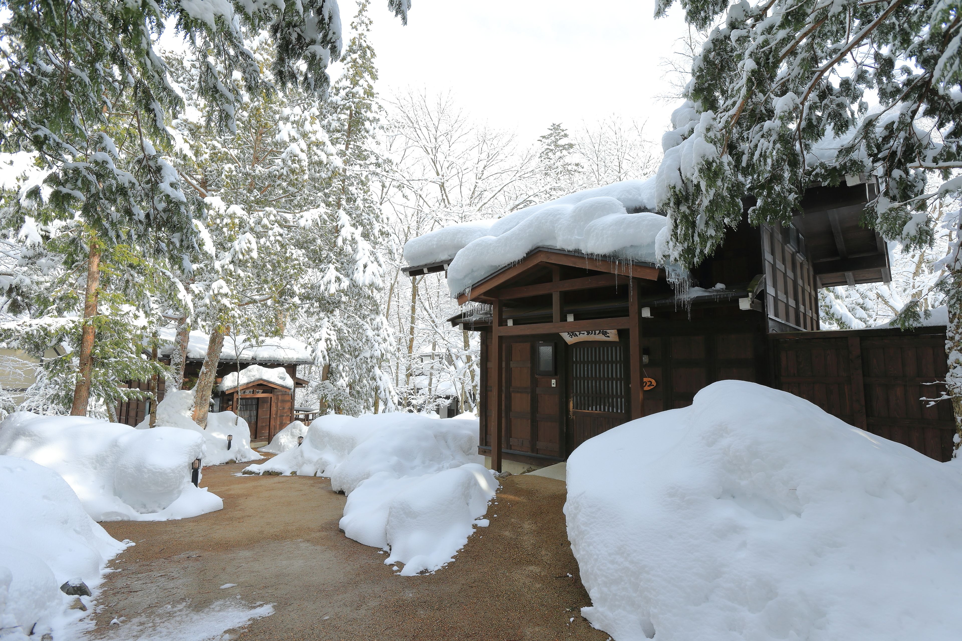 A snow-covered pathway leading to a wooden building with a traditional Japanese entrance.
