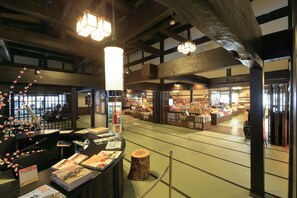 A bookstore with wooden beams and tatami mats, featuring bookshelves and a checkout counter. - Hirayunomori (Takayama)