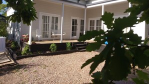 A two-story house with a covered patio area, large windows, and a gravel driveway. - Malley House (Healesville)