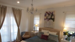 A bedroom with a large bed, a chair, a bedside table, a lamp, and a wall-mounted artwork. - Malley House (Healesville)