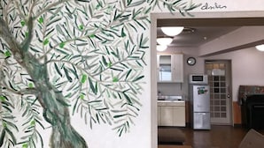 Un salon avec une grande fresque murale, un canapé, une table basse et, au fond, un espace cuisine.