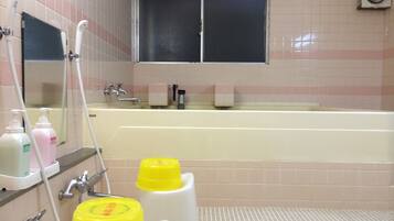 A bathroom with a bathtub, a mirror, a window, and toiletries on the counter.