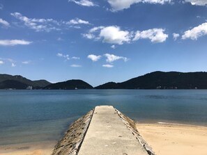 A concrete pier leading into calm waters with mountains in the background.
