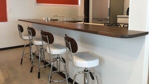 Una cuina moderna amb zona de bar, electrodomèstics d'acer inoxidable i una paret d'accent vermella.
