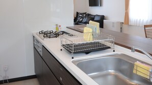 Una cuina moderna amb una campana d'extracció d'acer inoxidable, un doble mànec i una zona de menjador amb taula i cadires.