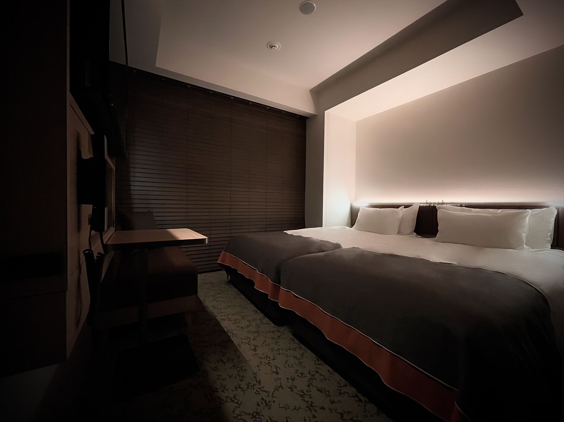A modern bedroom with a bed, bedside table, and a built-in bench.