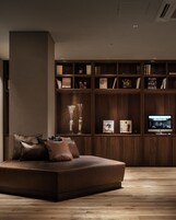 Una sala de estar moderna con una estantería empotrada de madera, un televisor de pantalla plana y un sofá de cuero.