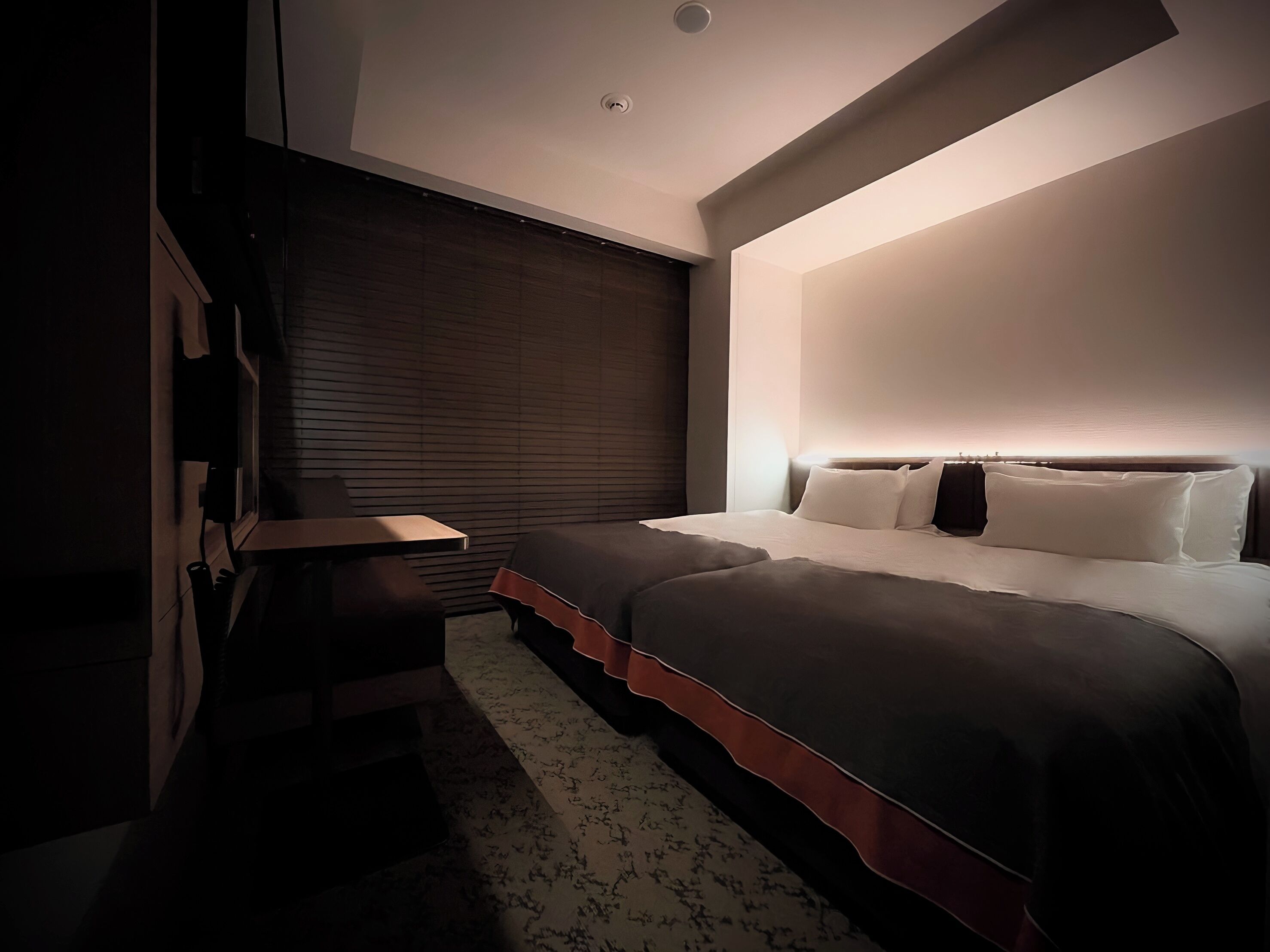Una camera da letto moderna con un letto, un comodino e una finestra con persiane.