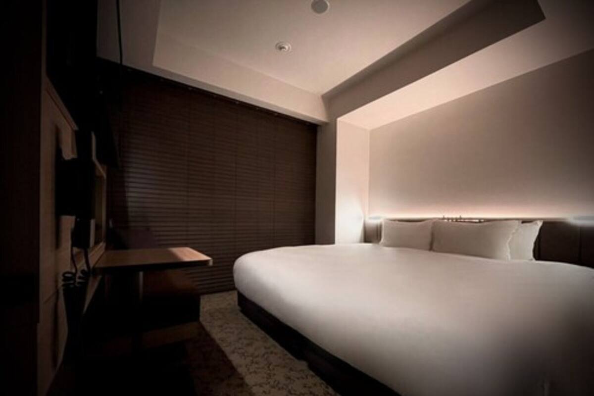 A modern bedroom with a large bed, a bedside table, and a wall-mounted TV.
