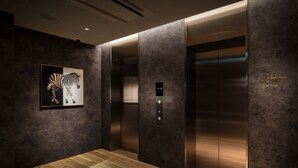A modern elevator interior with a zebra artwork on the wall, a digital display, and a wooden floor. - Nest Hotel Tokyo Hanzomon (Tokyo)