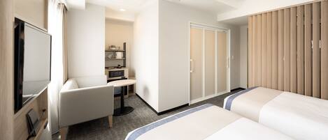 A hotel room with a bed, a desk, a chair, a wardrobe, and a television.
