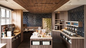 A modern kitchen with wooden cabinets, a central island with a sink, and a brick backsplash. - Tissage Hotel Naha (Naha)