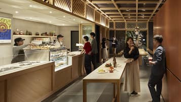Un interno di un caffè moderno con dettagli in legno, un lungo bancone e una zona con posti a sedere.