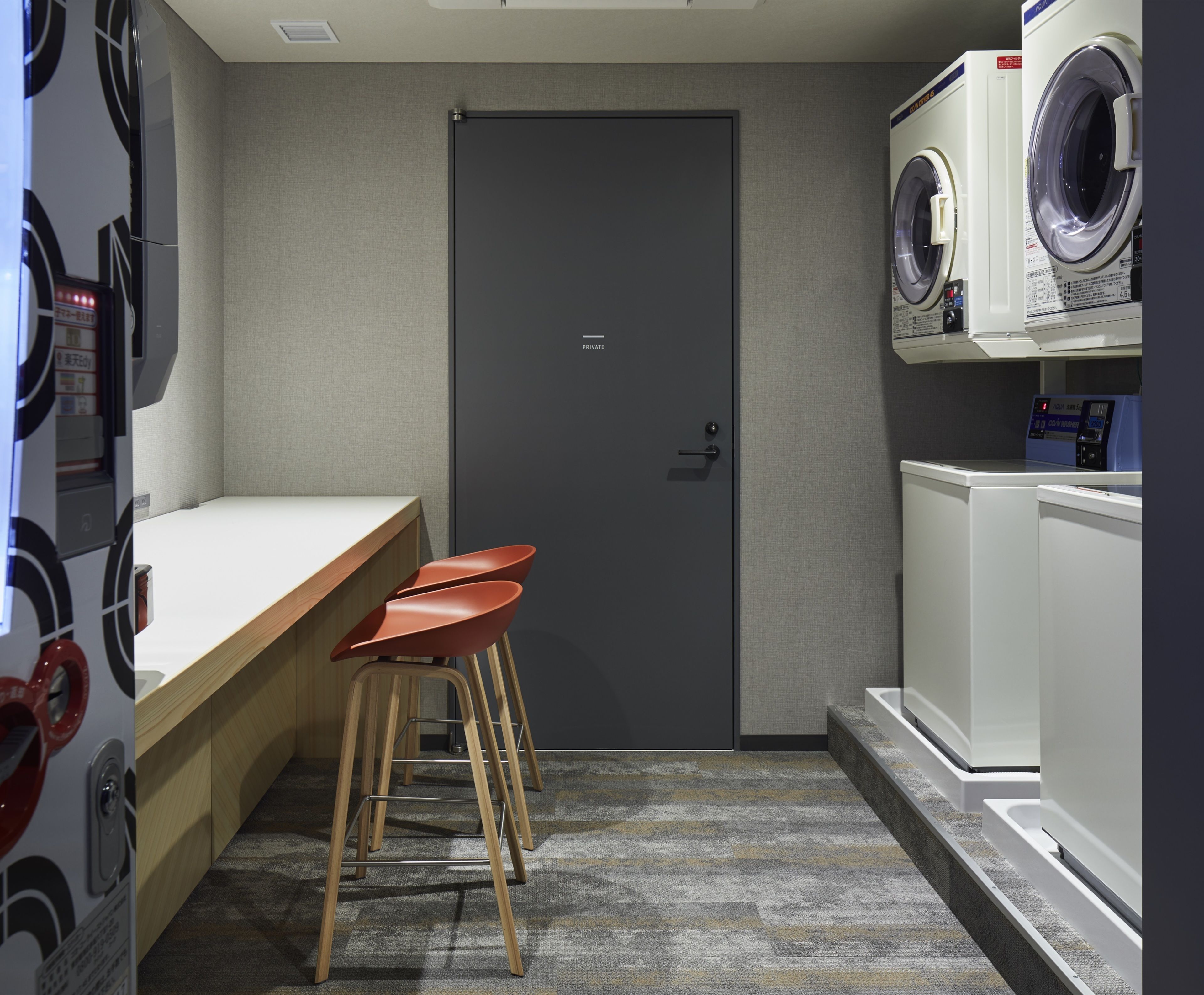 A compact laundry room with a washing machine, a dryer, and a small bar area with stools.